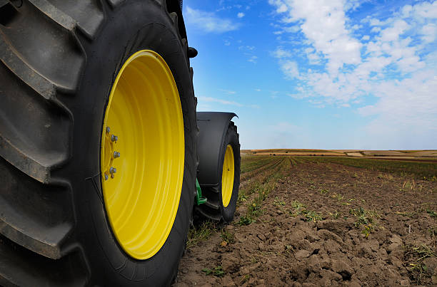 A large, advanced planting machine is seen working on a vast farmland.. The machinery's multiple components and precision technology highlight the efficiency and scale of modern farming practices. The expansive field and  sky emphasize the rural setting.