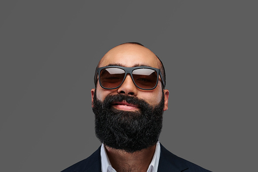 Close-up portrait of a bearded male in an elegant suit and sunglasses.