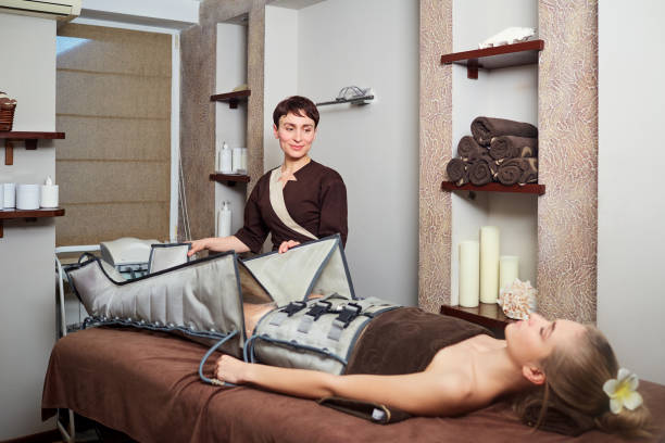 a woman lying down doing pressotherapy treatment - urgency body care young adult people imagens e fotografias de stock