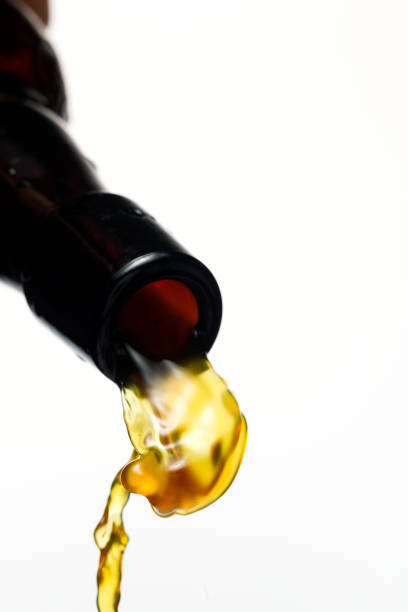 istock Dark beer is pouring from a bottle into a misted beer glass on a white background 916223526