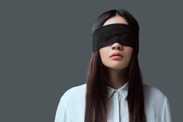 junge frau trägt schwarze augenbinde isoliert auf grau - verbundene augen stock-fotos und bilder