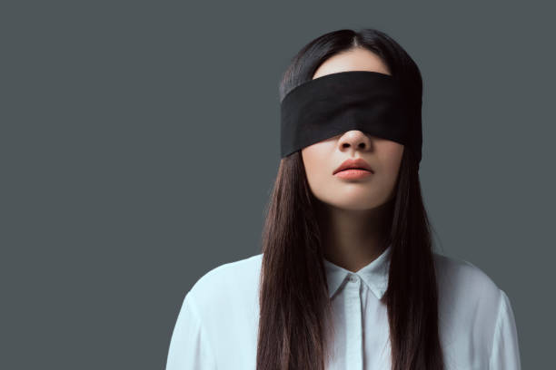 young woman wearing black blindfold isolated on grey stock photo