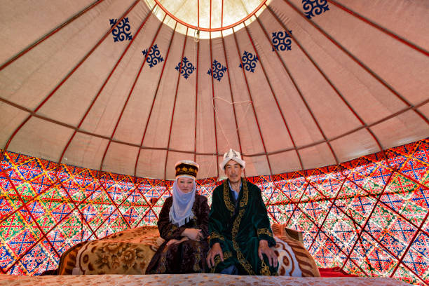 Kyrgyz couple in their yurt, Bishkek, Kyrgyzstan Bishkek, Kyrgyzstan - May 27, 2017: Kyrgyz couple in national costumes, in a nomadic tent known as yurt, near the city of Bishkek, Kyrgyzstan. bishkek stock pictures, royalty-free photos & images