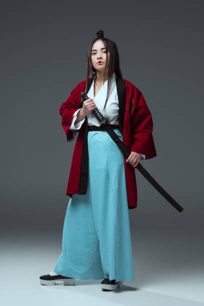 istock samurai in kimono holding katana sword and looking at camera on grey 916231098