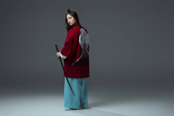 istock back view of samurai in kimono holding katana and looking at camera on grey 916231194