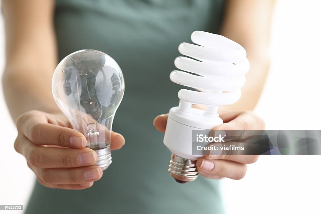 Hands holding traditional and energy efficent lightbulbs  Energy Efficient Lightbulb Stock Photo