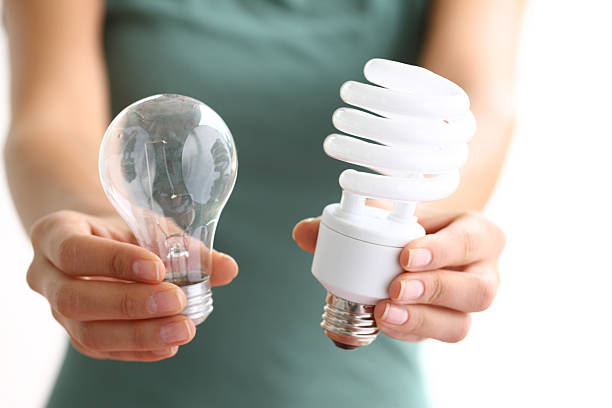 Hands holding traditional and energy efficent lightbulbs  energy efficient lightbulb stock pictures, royalty-free photos & images