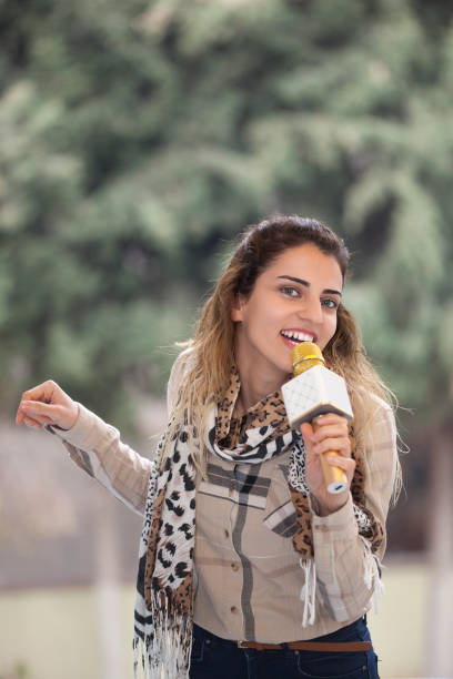 istock Young woman holding microphone and singing 916238792