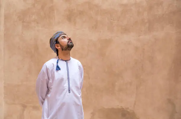 arab man in traditional omani outfit looking up