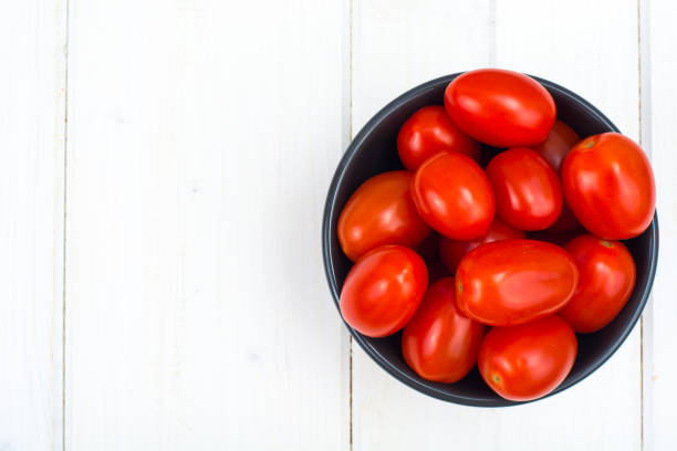 istock Small red ripe tomatoes in bowl on wooden table, top view 916245358