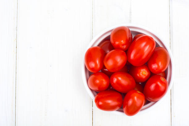 istock Small red ripe tomatoes in bowl on wooden table, top view 916245422
