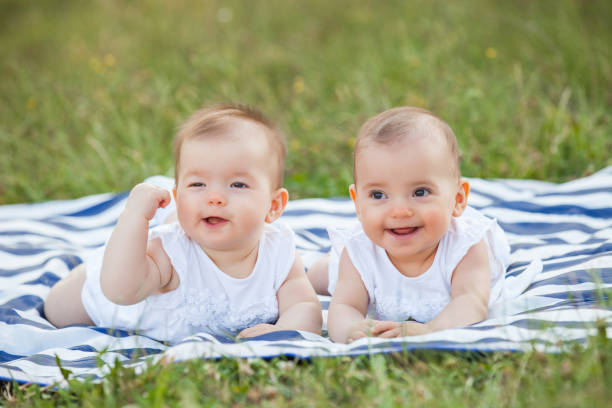cute baby girls at the park laying on the blanket