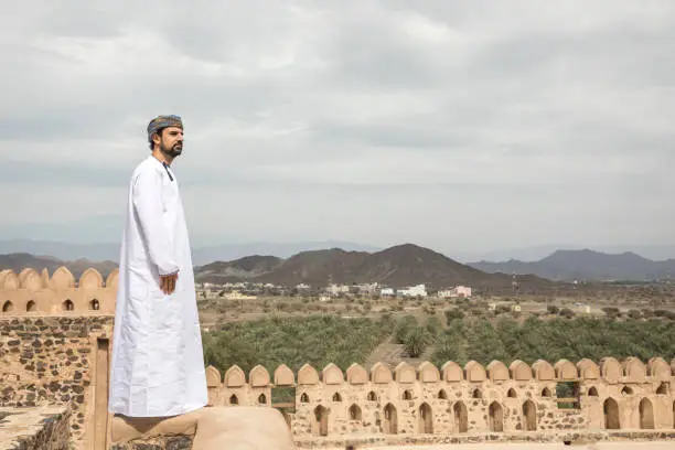 arab man in traditional omani outfit overlooking the countryside of Oman