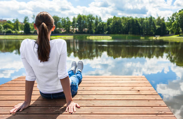 istock Young woman relaxing by the lake 916252900