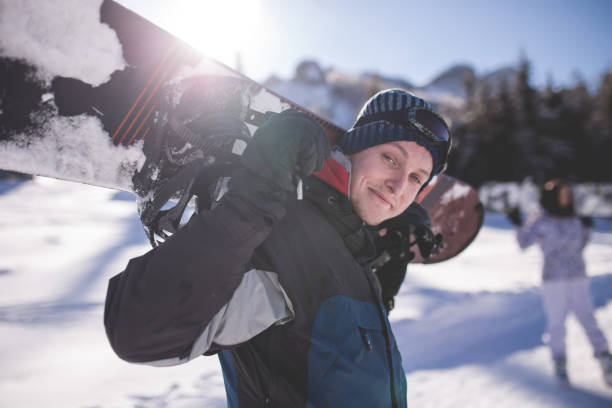 istock Snowboarder Posing Cheerfully With His Snowboard 916256190