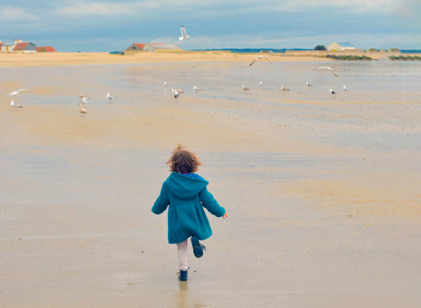 A lovely little girl playing in the sand on the beach.Happy with her family.
