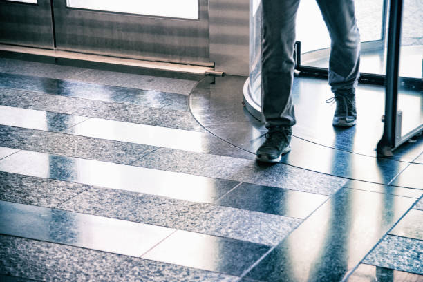 Office Building Lobby Entrance Abstract A man walking through a glass revolving door into a modern office building lobby. bank entrance stock pictures, royalty-free photos & images