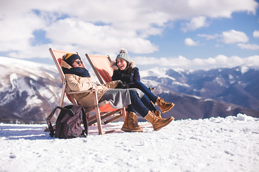 Happy Young Women Enjoying Carefree Sitting In Outdoor Chairs On Top Of Mountain