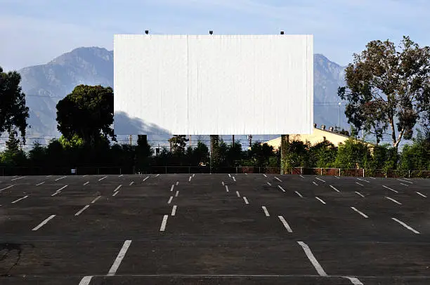 Image of a large movie screen at a drive in theater.