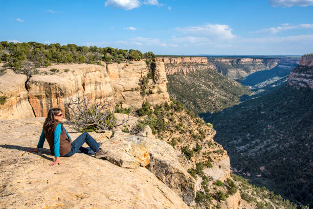 Woman relaxing on slick rock at the edge of Mesa Verde. Southwest Colorado.
