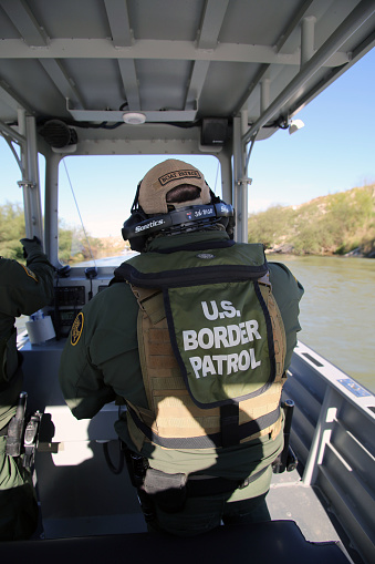 McAllen, Texas, USA - January 29, 2018: A Border Patrol agent drives a small river patrol boat monitoring the Rio Grande River for illegal aliens crossing into the U.S. Such encounters are a daily experience in the Rio Grande Valley sector of Border Patrol operations.