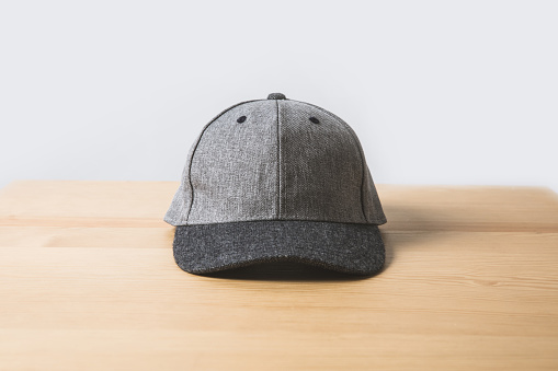one grey cap on wooden table on white
