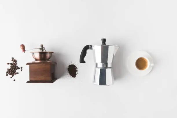 top view of arranged coffee making supplies, ingredients and cup of coffee on white tabletop
