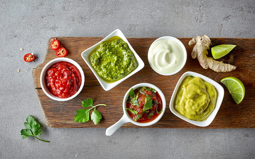 various dip sauces on grey table, top view