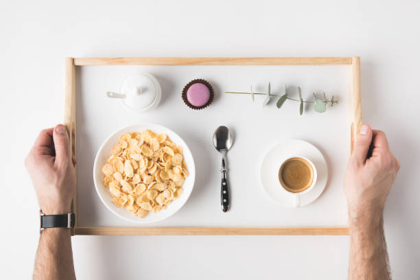 cropped shot of man holding tray with breakfast on white surface