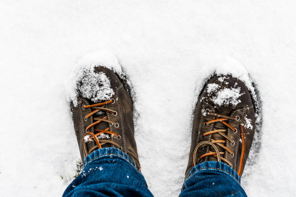 istock Feet and leather brown boots on white snow 916300548