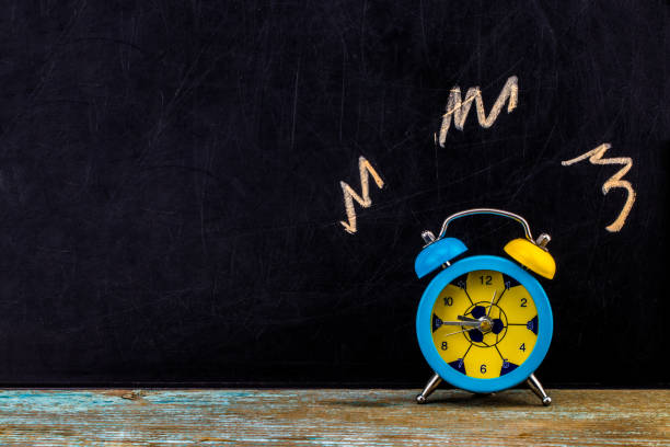 istock Ringing alarm clock on dark background, suggesting wake-up time or deadline.With copy space 916301042