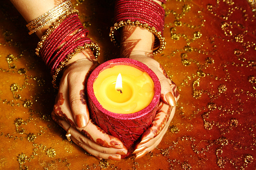Hands of an Indian woman holding a candle.