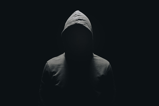 hombre sin rostro en sudadera con capucha de pie aislado en negro photo
