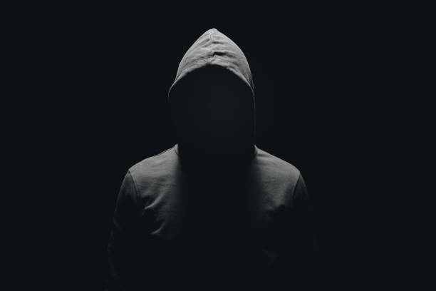 homme sans visage en hoodie debout, isolée sur fond noir - capuche photos et images de collection