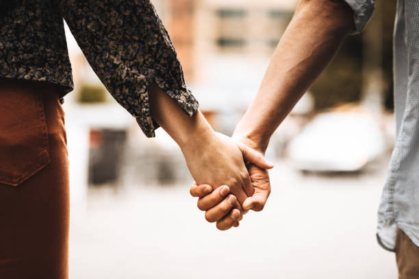 achteraanzicht van een paar lopen op straat - romantic stockfoto's en -beelden