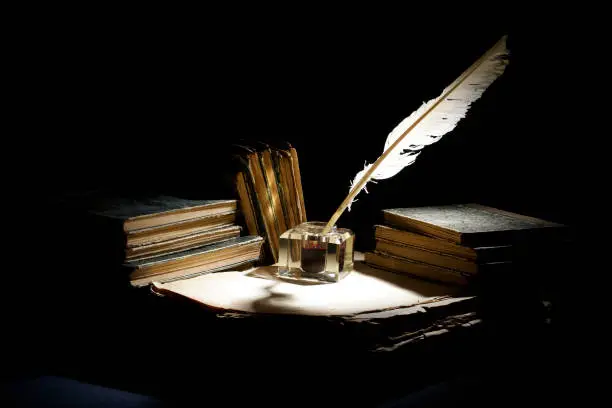 Vintage concept. Old fountain pen, books and inkwell on a black background