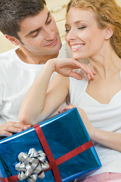 Young happy amorous couple with gift at home stock photo