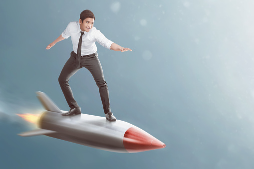 Portrait of asian businessman standing on flying rocket on the sky background