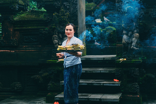 Balinese woman in sarong  giving offerings in the temple in Bali, Indonesia