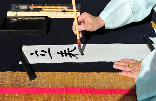 A korean calligrapher in the middle of writing in Chinese. The Chinese script in the picture is Ipchun (Onset of spring).