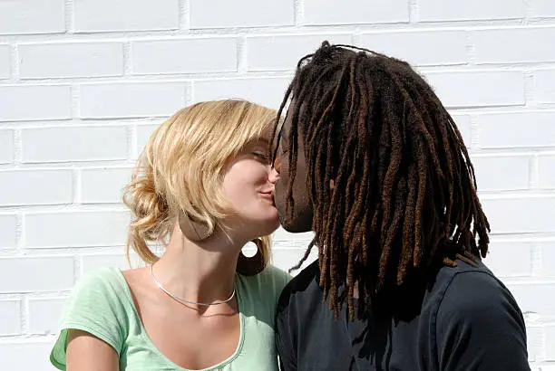 Photo of young kissing black & white couple