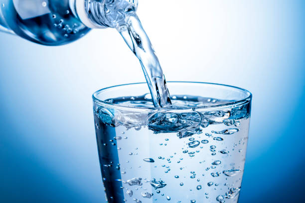 pour carbonated water into a glass - water water bottle glass pouring imagens e fotografias de stock