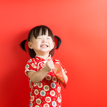 Little Asian girl holding red envelope on red background
