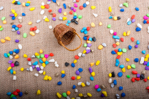 istock Basket and spilled colorful pebbles  on canvas background 916393492