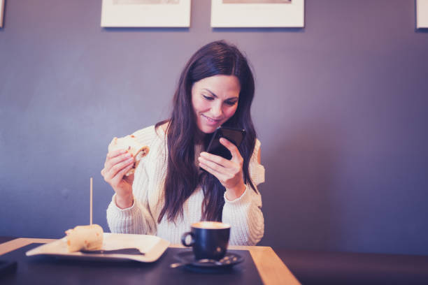 istock Young women having breakfast in cafe, using smart phone 916396832