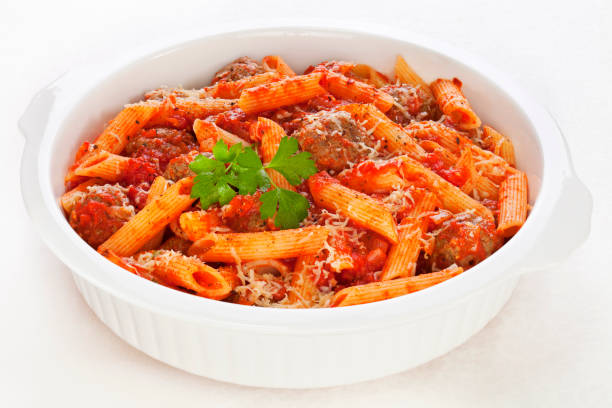 Pasta with Meatballs Meatballs in tomato sauce with penne pasta and parmesan cheese, baked in the oven. penne meatballs stock pictures, royalty-free photos & images