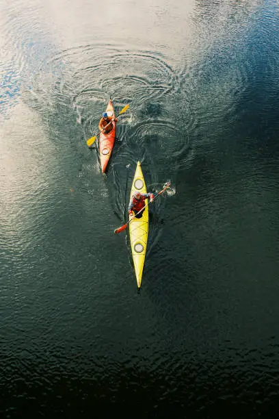 Two men are kayaking along the river.