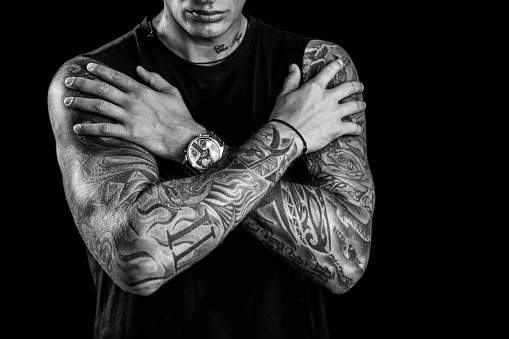 Young man with tatoo sleeves posing in studio, isolated on black background. About 25 years old, Caucasian male.