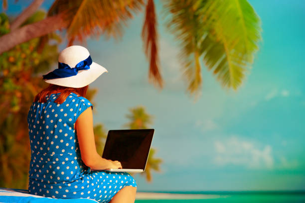 istock young woman with laptop on beach 916407992