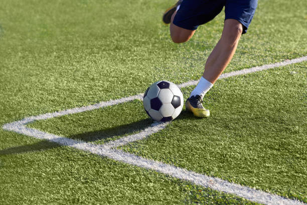 Footballer is preparing to give a corner kick with the ball Footballer is preparing to give a corner kick with the ball on the goal on the green grass, playing on the football field. 2018 stock pictures, royalty-free photos & images